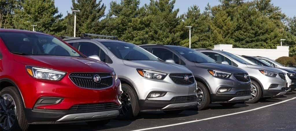 Row of parked SUVs in various colors on an outdoor lot, with trees in the background.