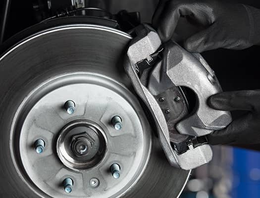 Mechanic adjusting a brake caliper on a car's brake system.