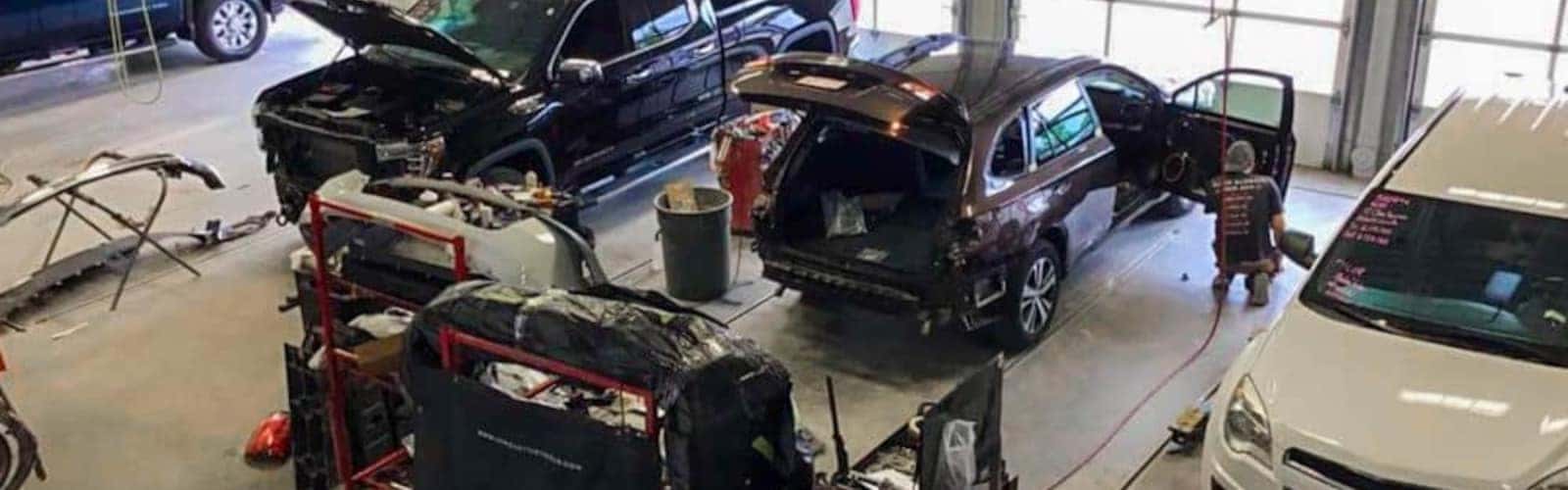 Auto repair shop with cars under maintenance, open hoods, and a technician working nearby.