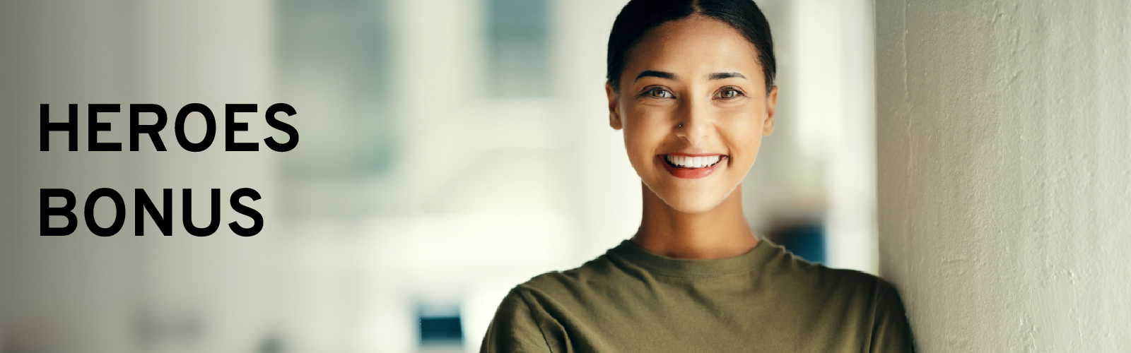 Smiling person standing near a wall; text reads "Heroes Bonus".